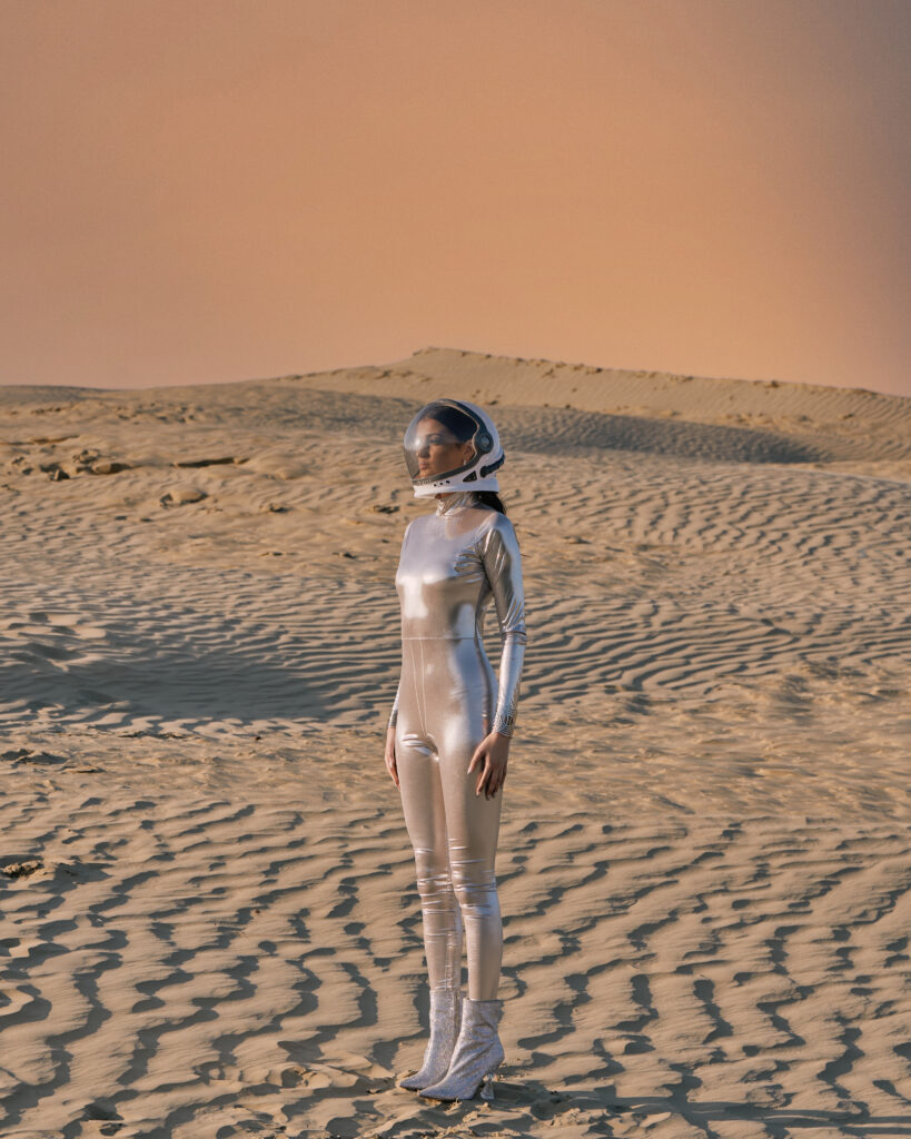 Photo of model in spacesuit with desert backgorund.