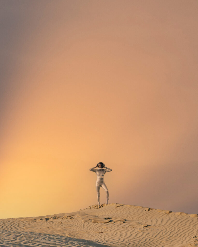 Photo of model in spacesuit with desert backgorund.