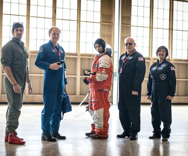 Photo of Pandya in spacesuit alongside group of colleagues in aerospace industry.